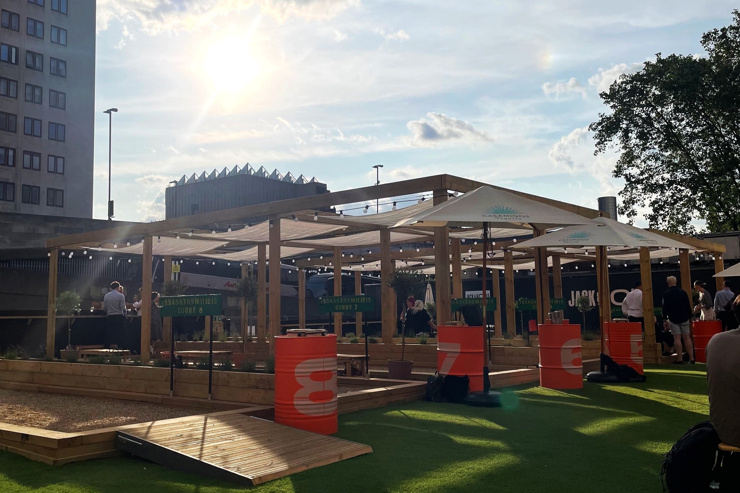 Vibrant outdoor networking event space with wooden structure and greenery.