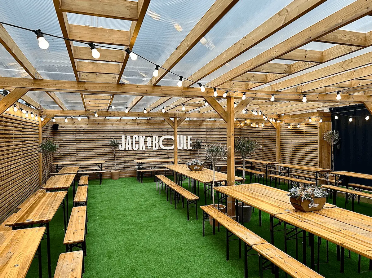 Outdoor event space with wooden beams, ideal for gatherings and corporate events.