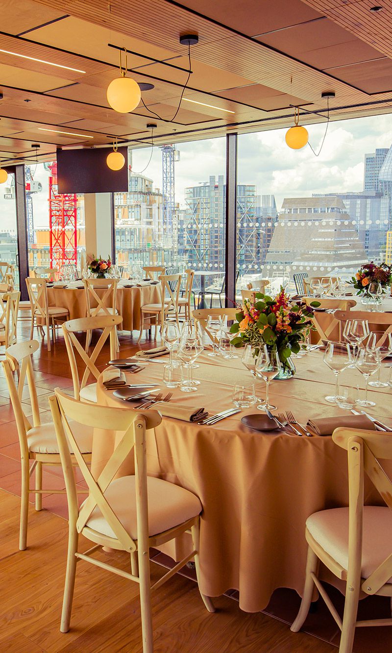 Elegant event space with floral centerpieces and city view for weddings and corporate events.