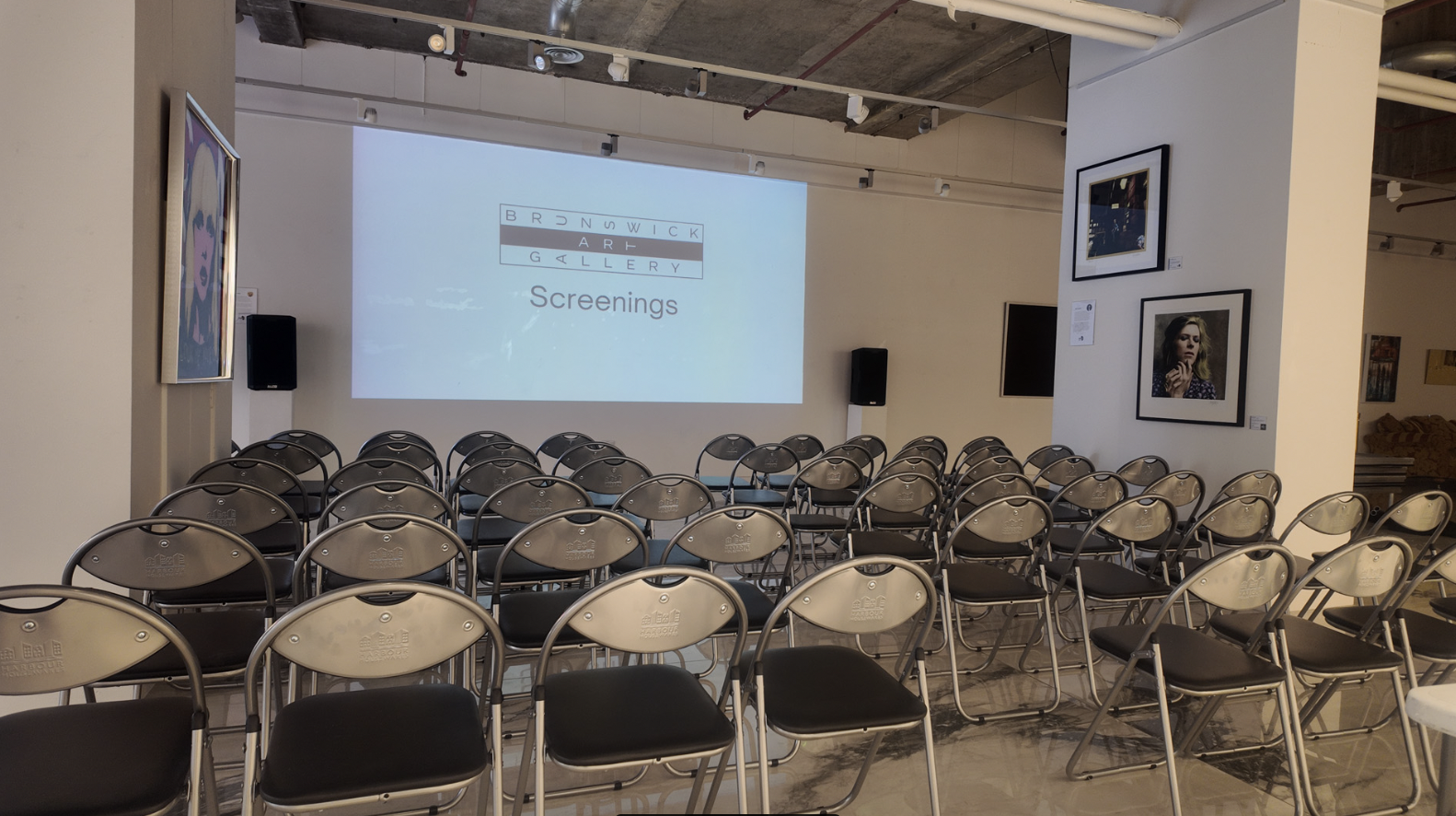 Brunswick Art Gallery event space with metal chairs and projection screen for presentations.