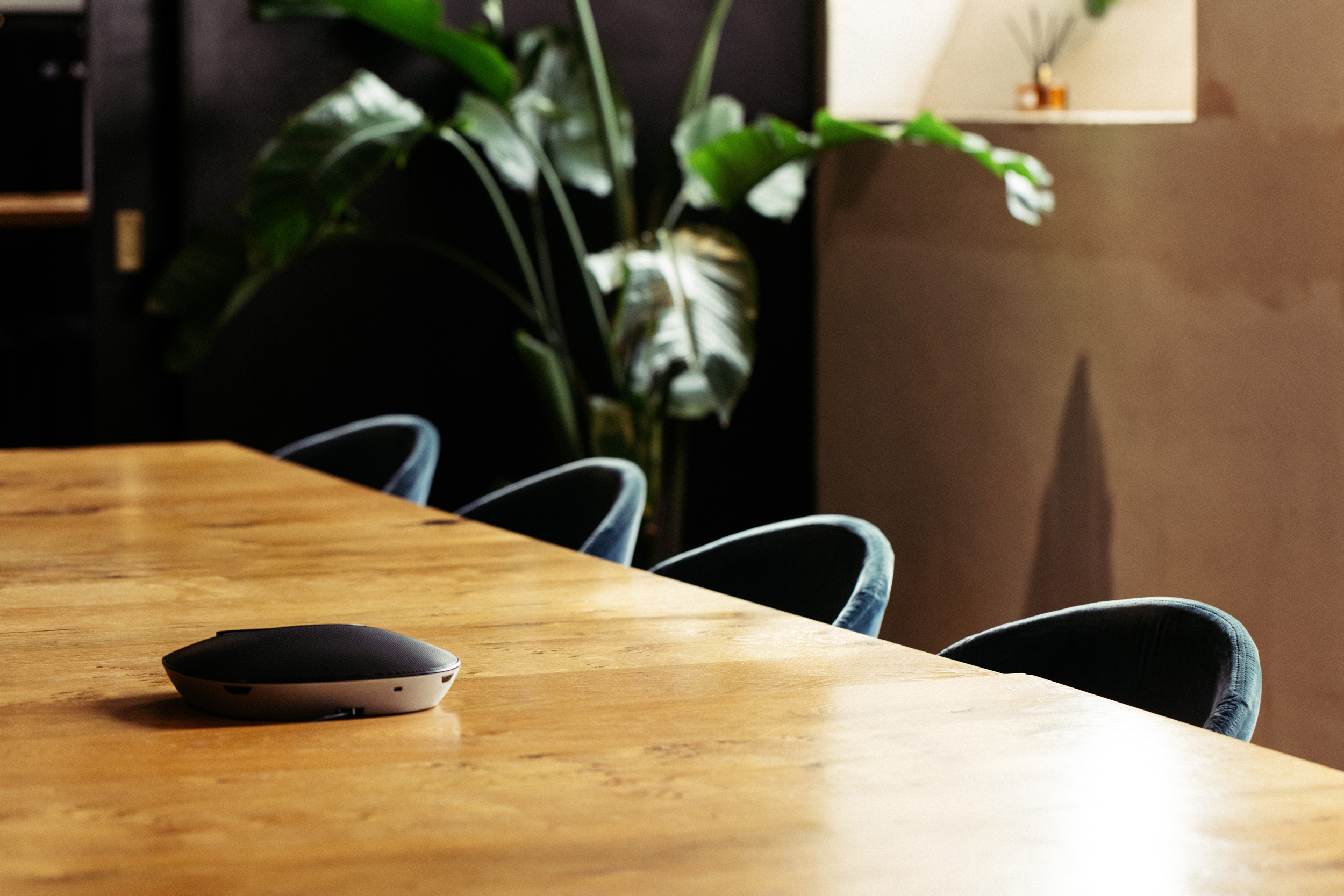 Modern conference room with sleek table, audio device for hybrid meetings.
