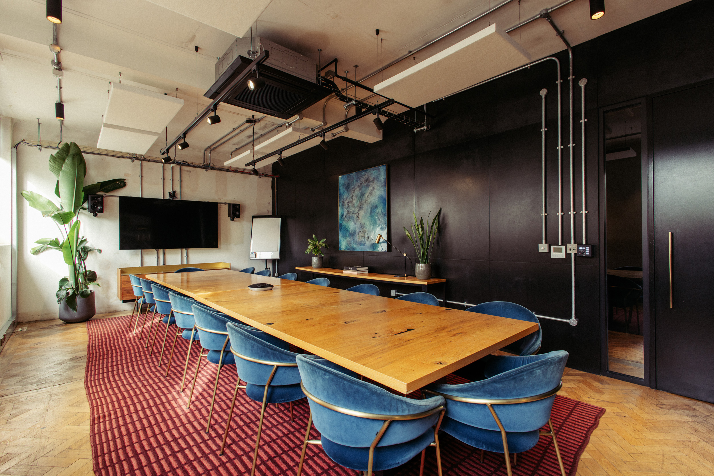 Modern meeting room with wooden table and blue chairs, perfect for events and collaboration.