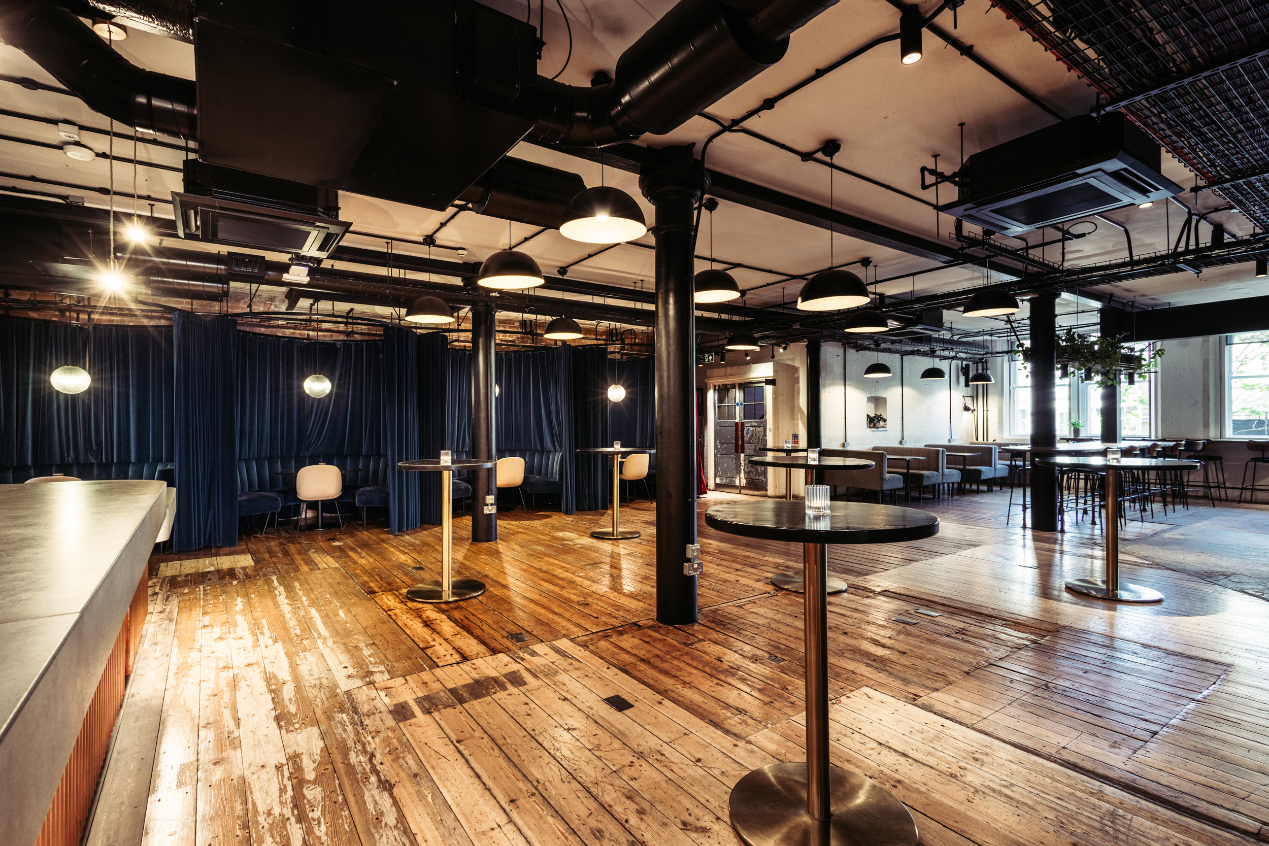 Versatile event space with polished wooden floors, ideal for networking and gatherings.