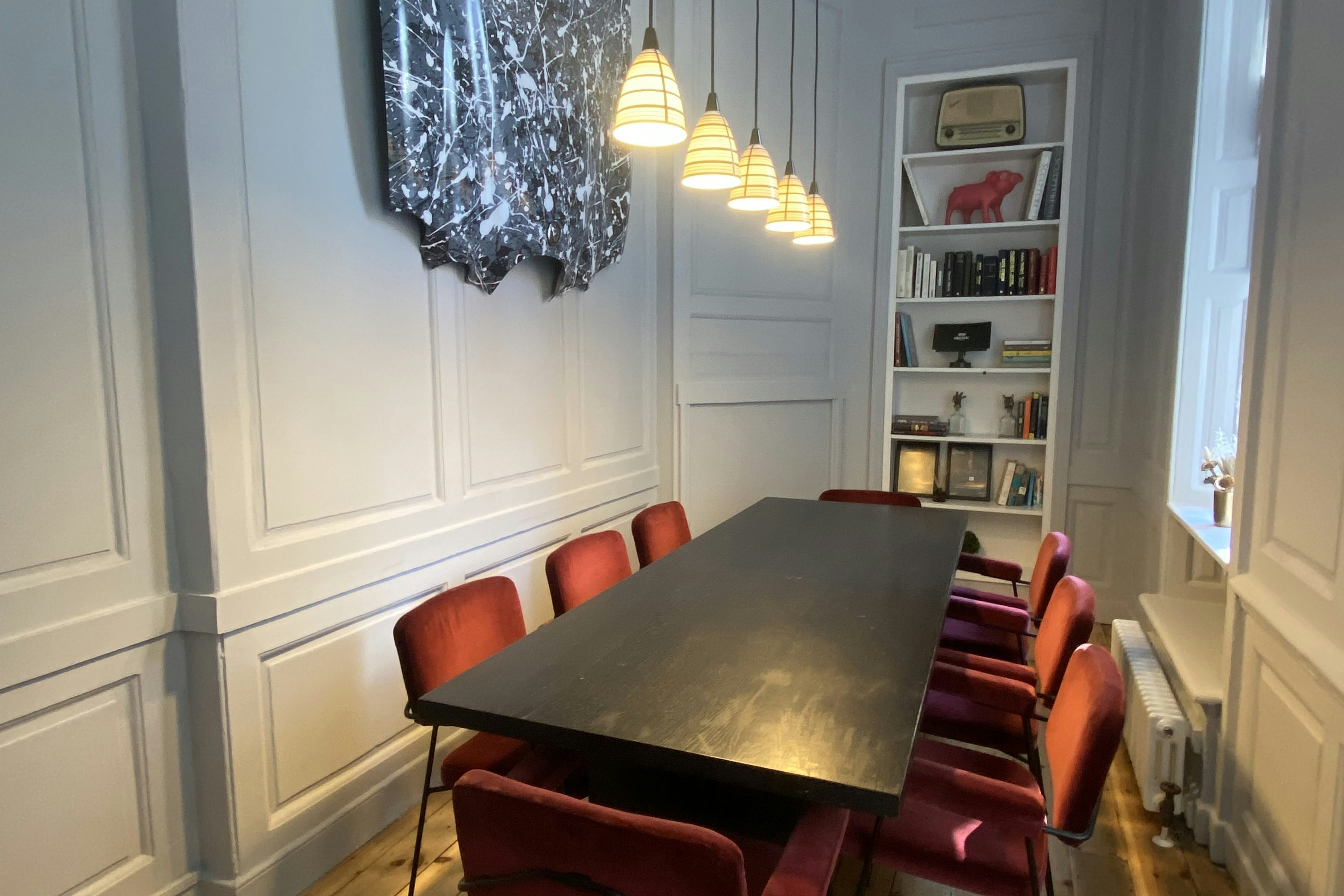 Stylish meeting room with dark table and red chairs, perfect for executive gatherings.