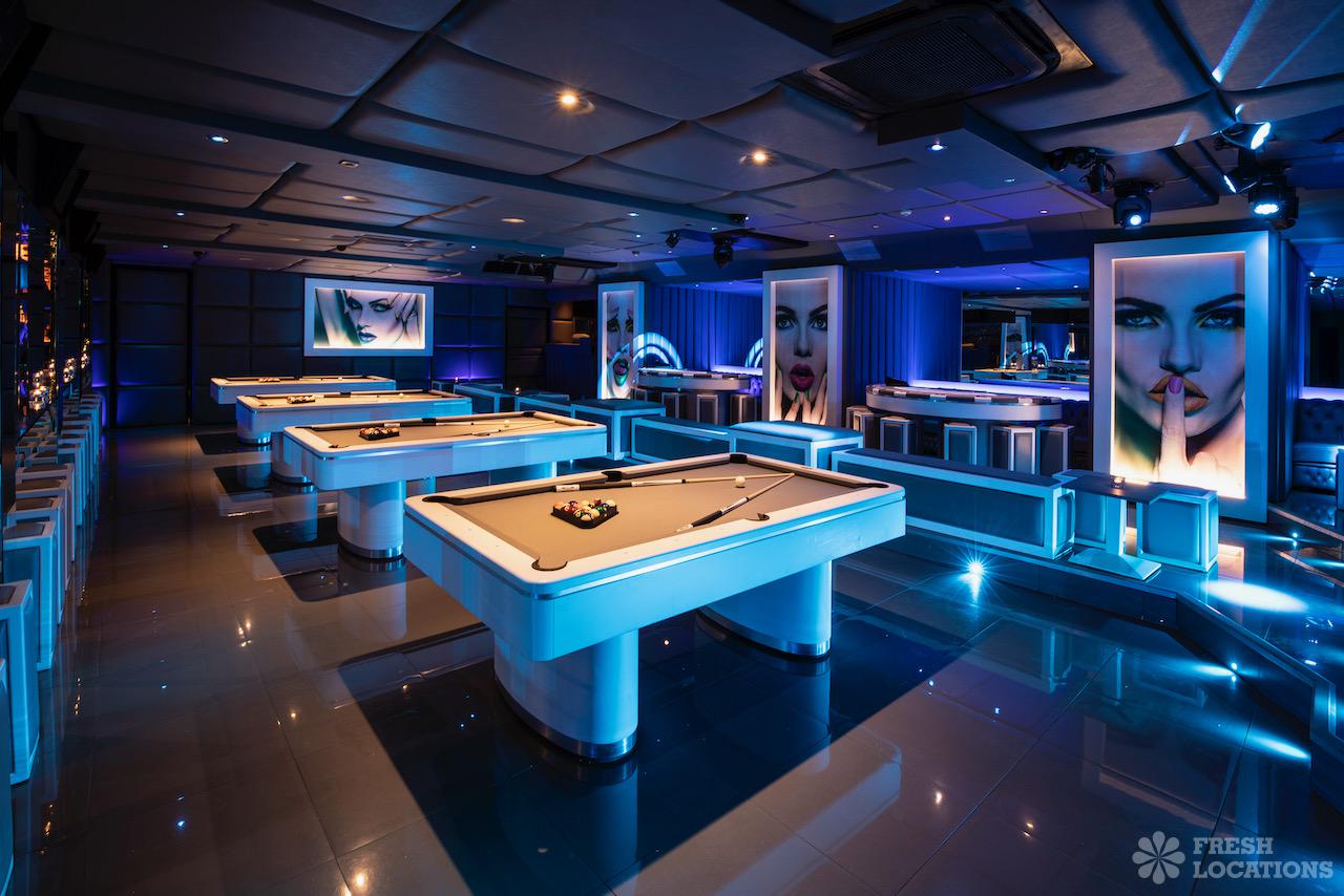 Modern event space with pool tables and ambient blue lighting for gatherings.