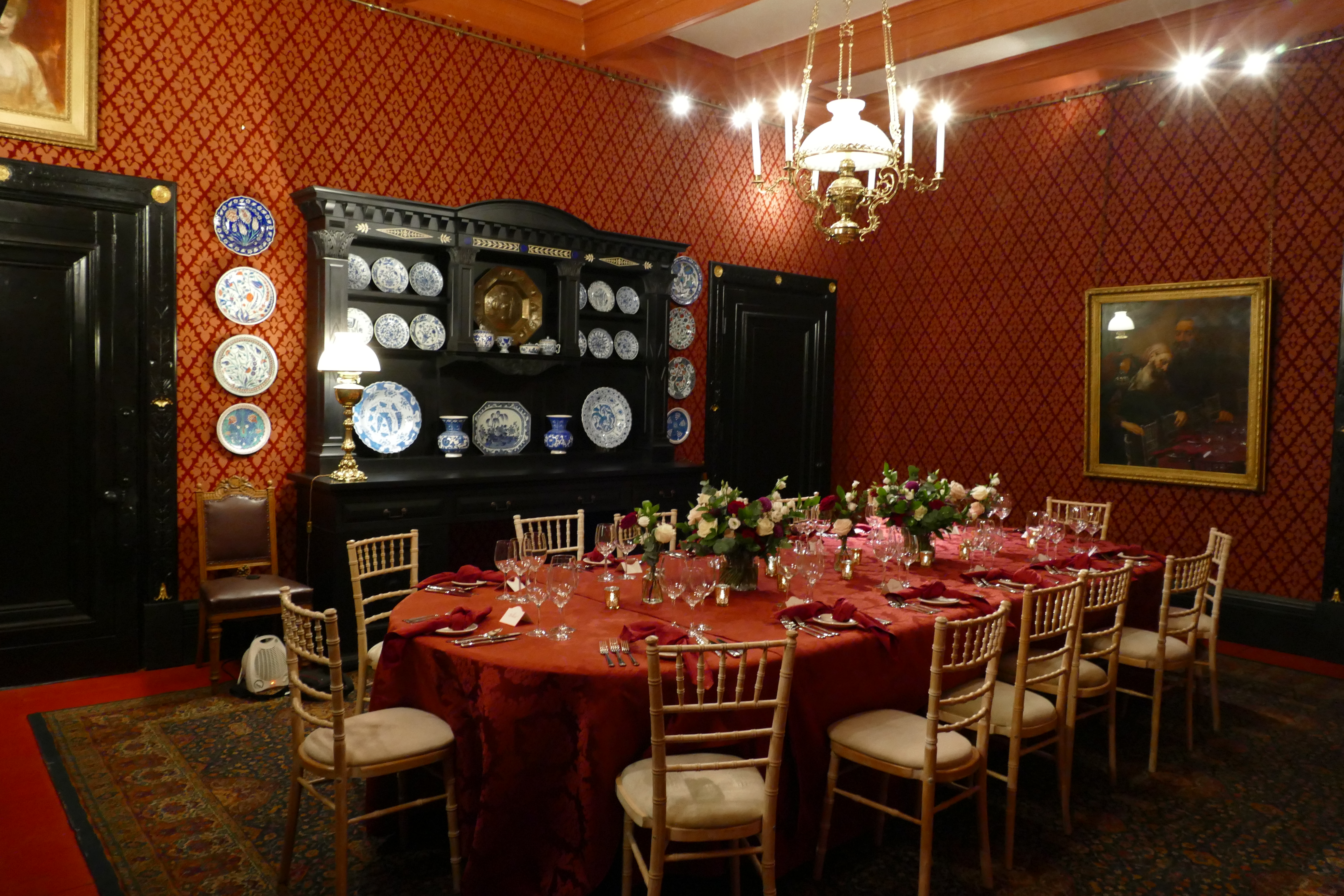 Elegant dining room at Leighton House with rich red walls, ideal for corporate events.