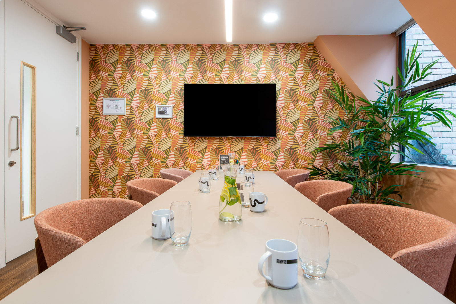 Modern meeting room with long table, vibrant wallpaper for collaborative events.
