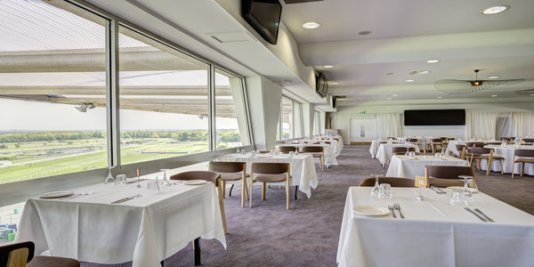 Elegant dining area at Sandown Park for corporate events with large windows and AV equipment.