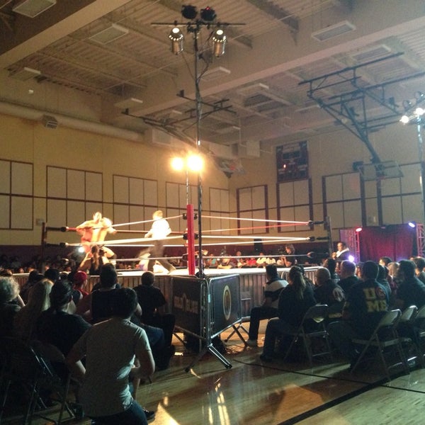 Wrestling event at Bayshore Community Center with spotlighted ring and engaged audience.