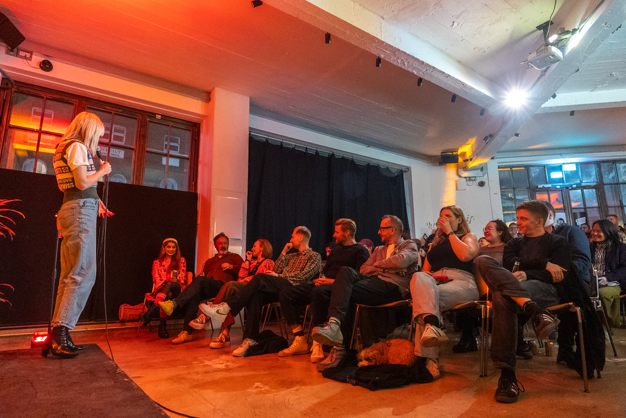 Engaging speaker at lively networking event in Kachette Shoreditch, warm lighting.