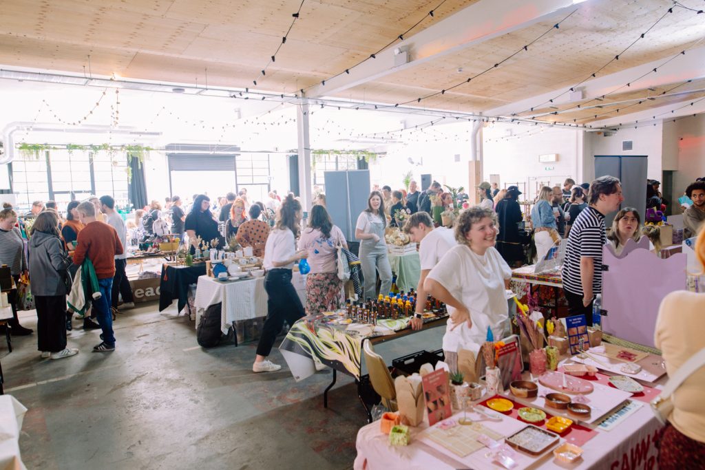 Vibrant outdoor event space with attendees networking and showcasing local vendors.