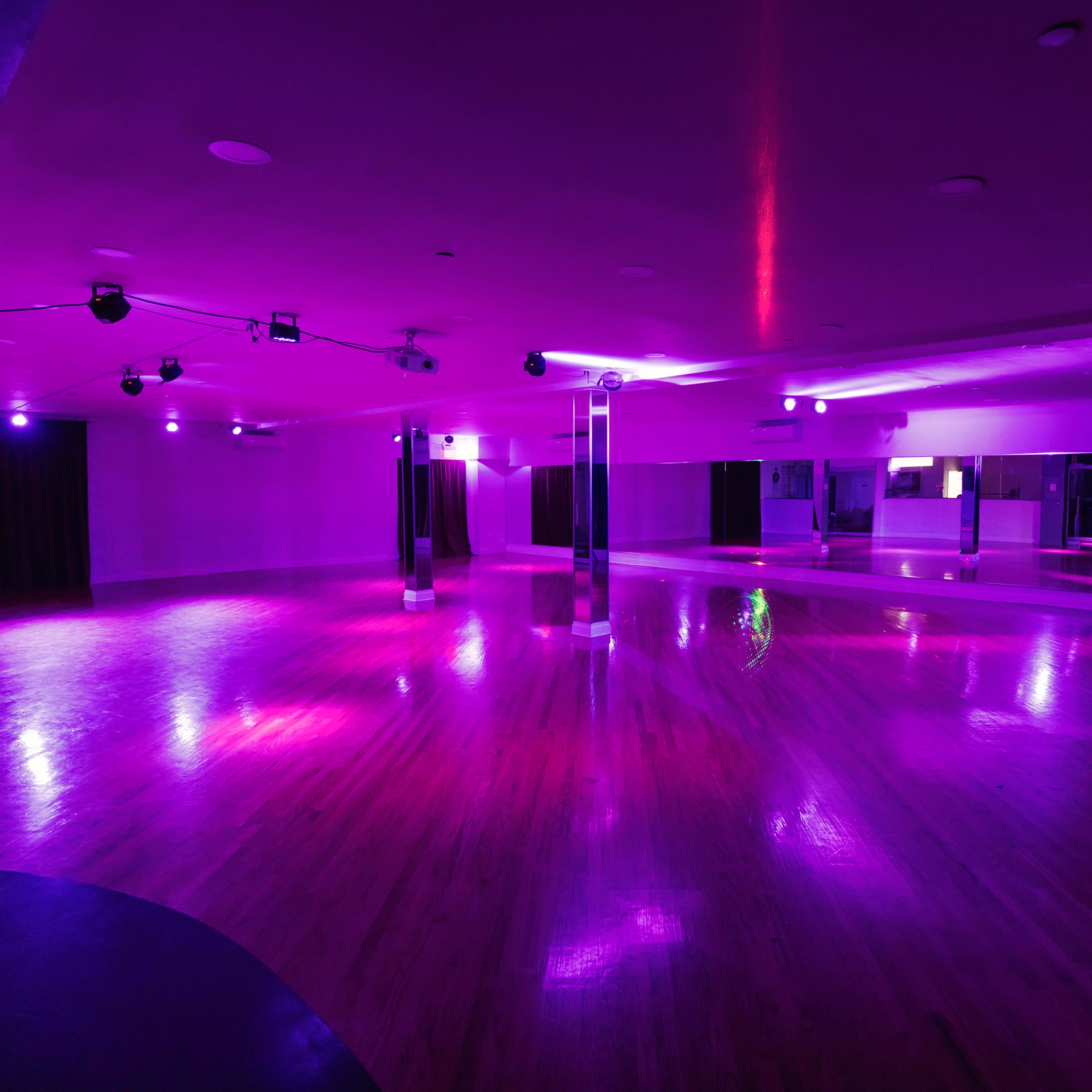 Versatile event space with polished floors and purple lighting for dynamic gatherings.