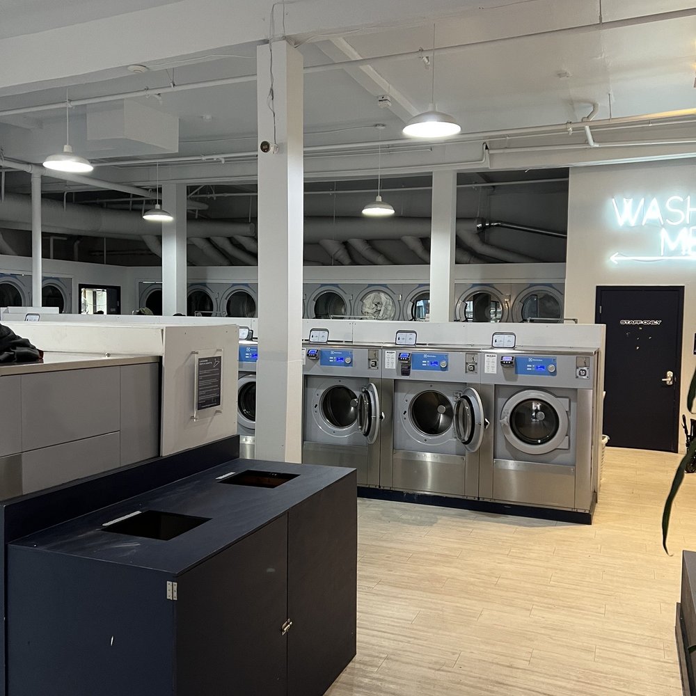 Modern laundromat with stainless steel machines, ideal for networking events and meet-ups.