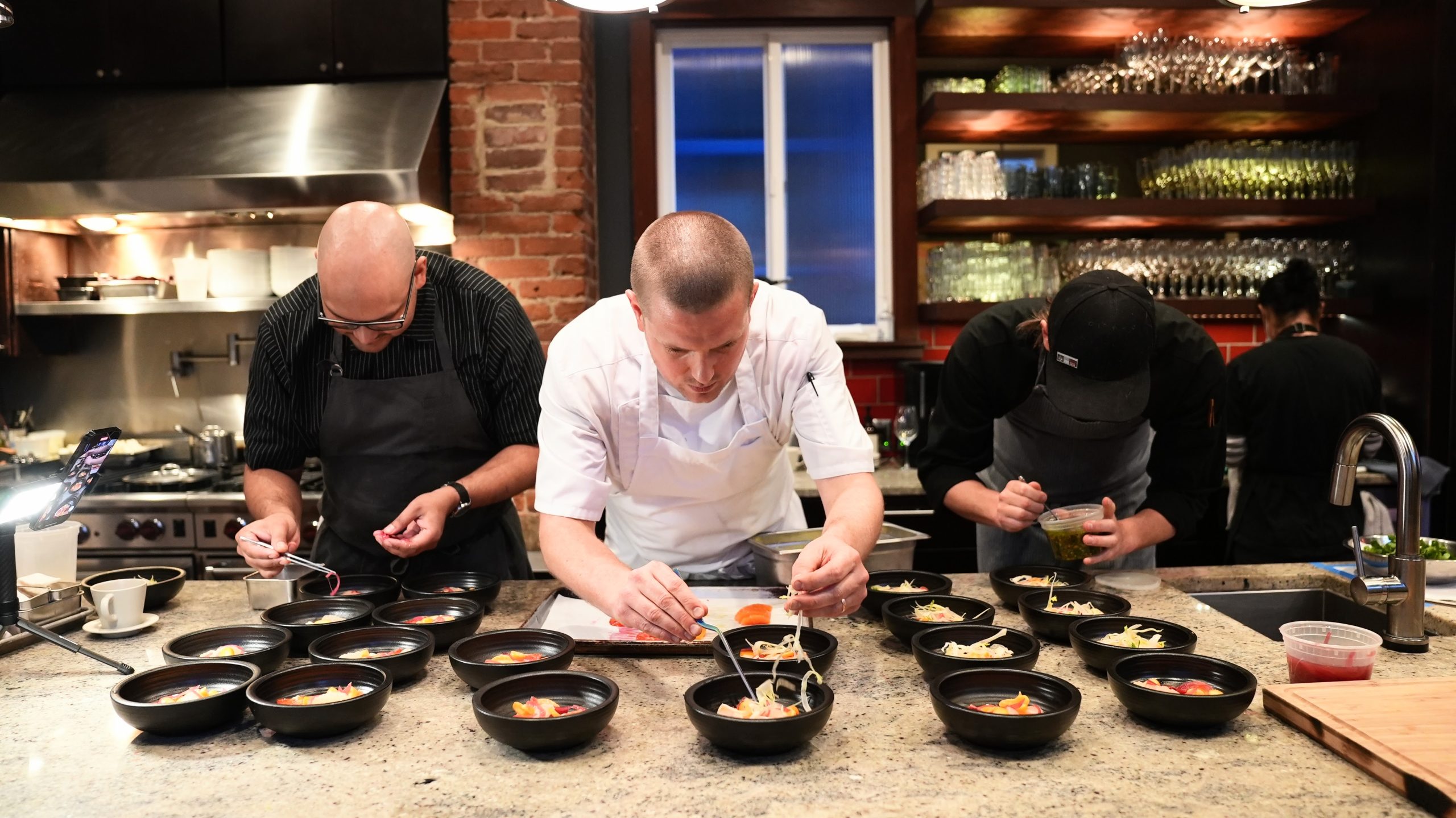 Chefs plating dishes in Naked Kitchen's Upstairs Room for exclusive culinary events.