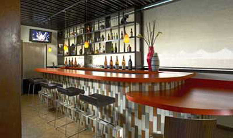 Modern hotel lobby lounge with vibrant orange bar, ideal for networking events and gatherings.