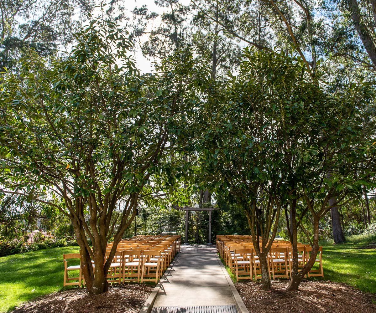 Outdoor garden ceremony space at Presidio Chapel with wooden chairs, perfect for weddings.