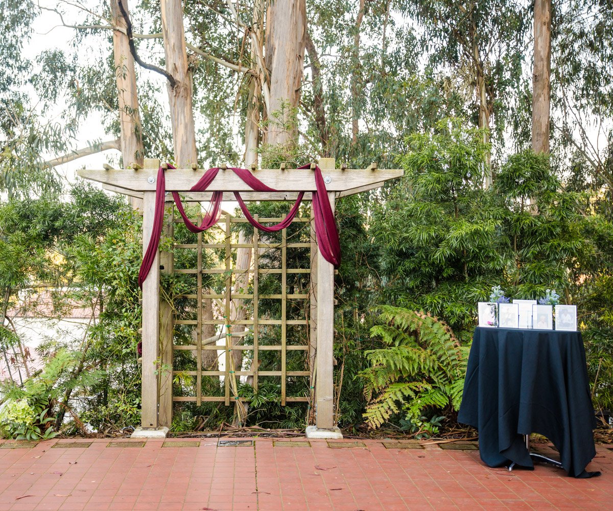 Outdoor garden event space with wooden arbor, perfect for weddings and gatherings.