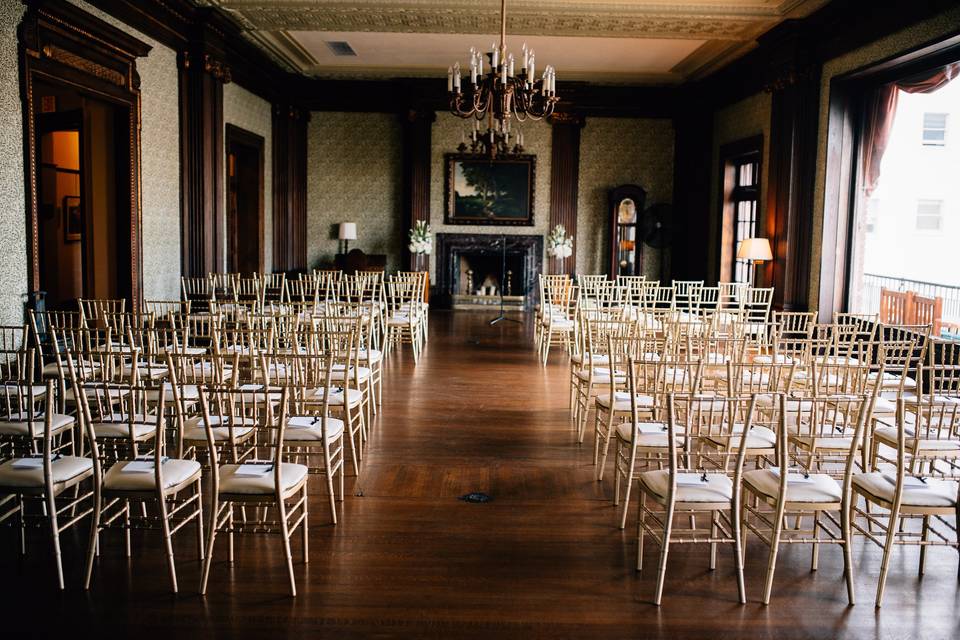 Elegant event venue with wooden flooring and gold chiavari chairs, ideal for weddings and ceremonies.