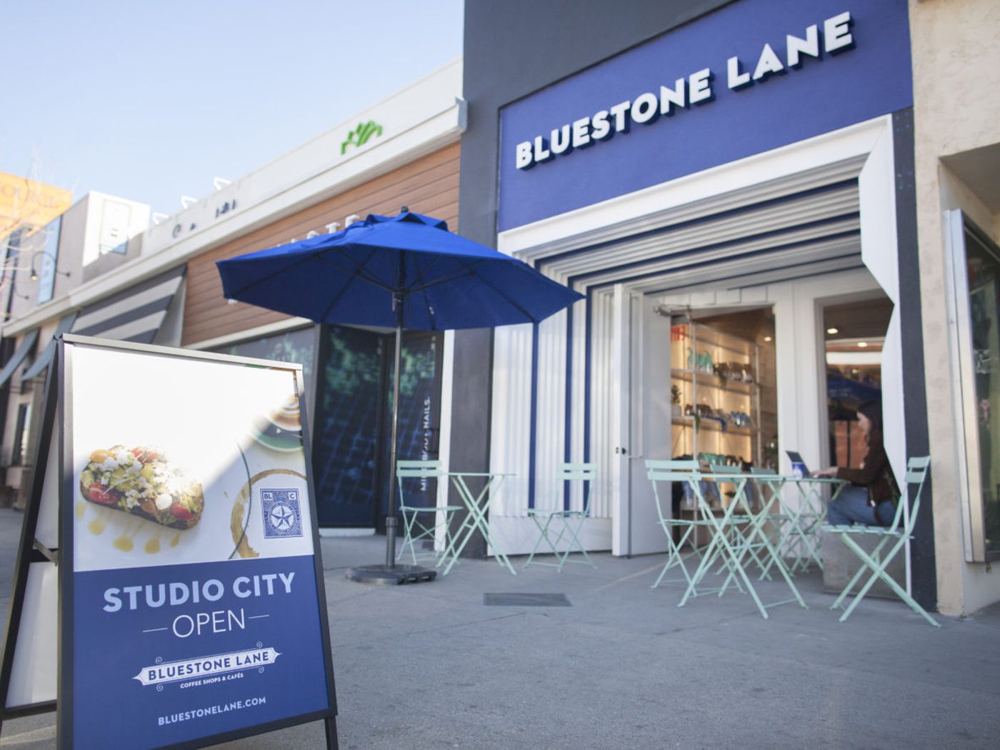 Bluestone Lane storefront in Studio City with teal chairs, perfect for casual meetings.