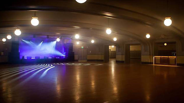 Elegant vintage event space with polished wood floor, ideal for gatherings and performances.