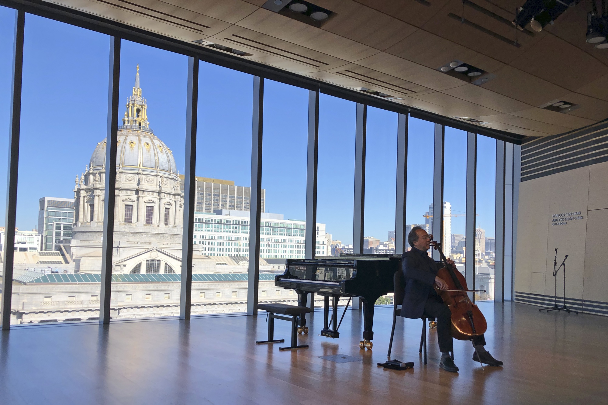 Musician performing with grand piano in elegant event space with city skyline view.