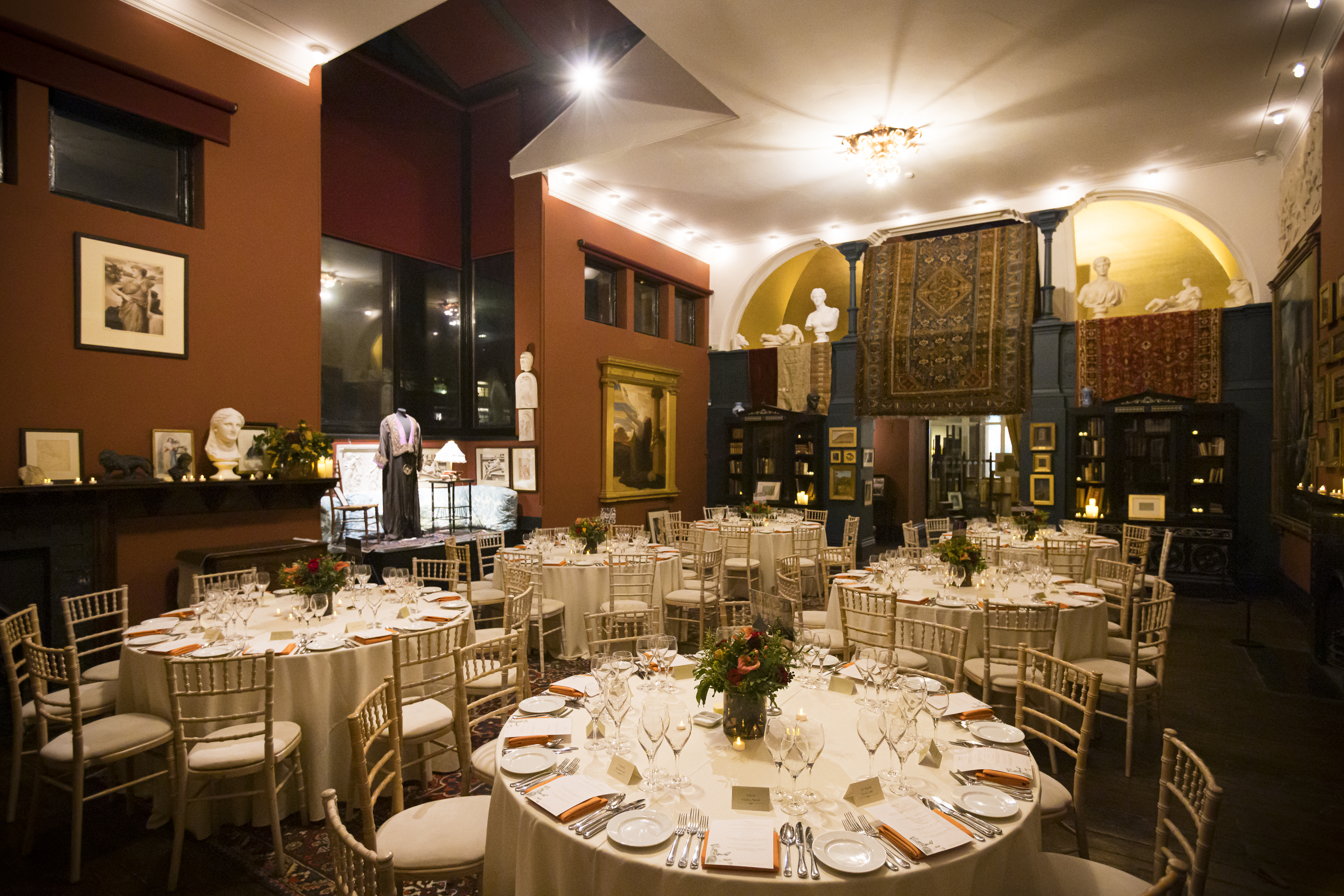 Elegant Christmas party space with round tables and floral centerpieces at Leighton House.