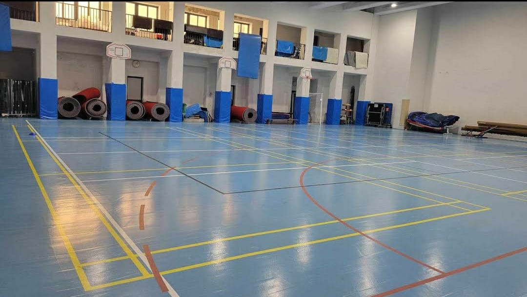 Indoor badminton/volleyball court with polished blue flooring for events and team-building activities.
