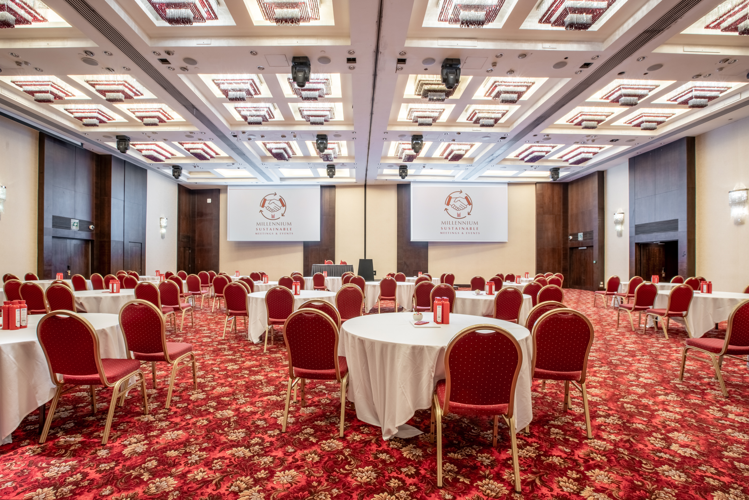 Spacious conference venue with round tables and red chairs in London. Ideal for events.