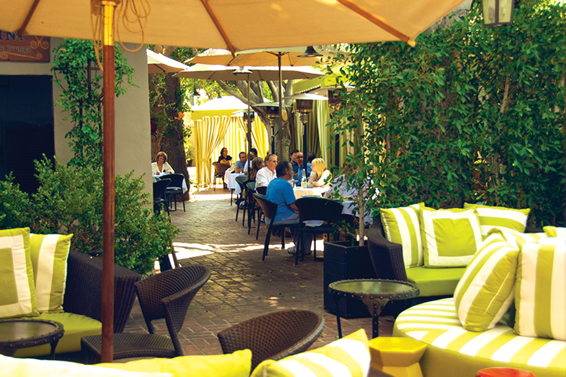 Private outdoor dining space with lush greenery for casual networking events.