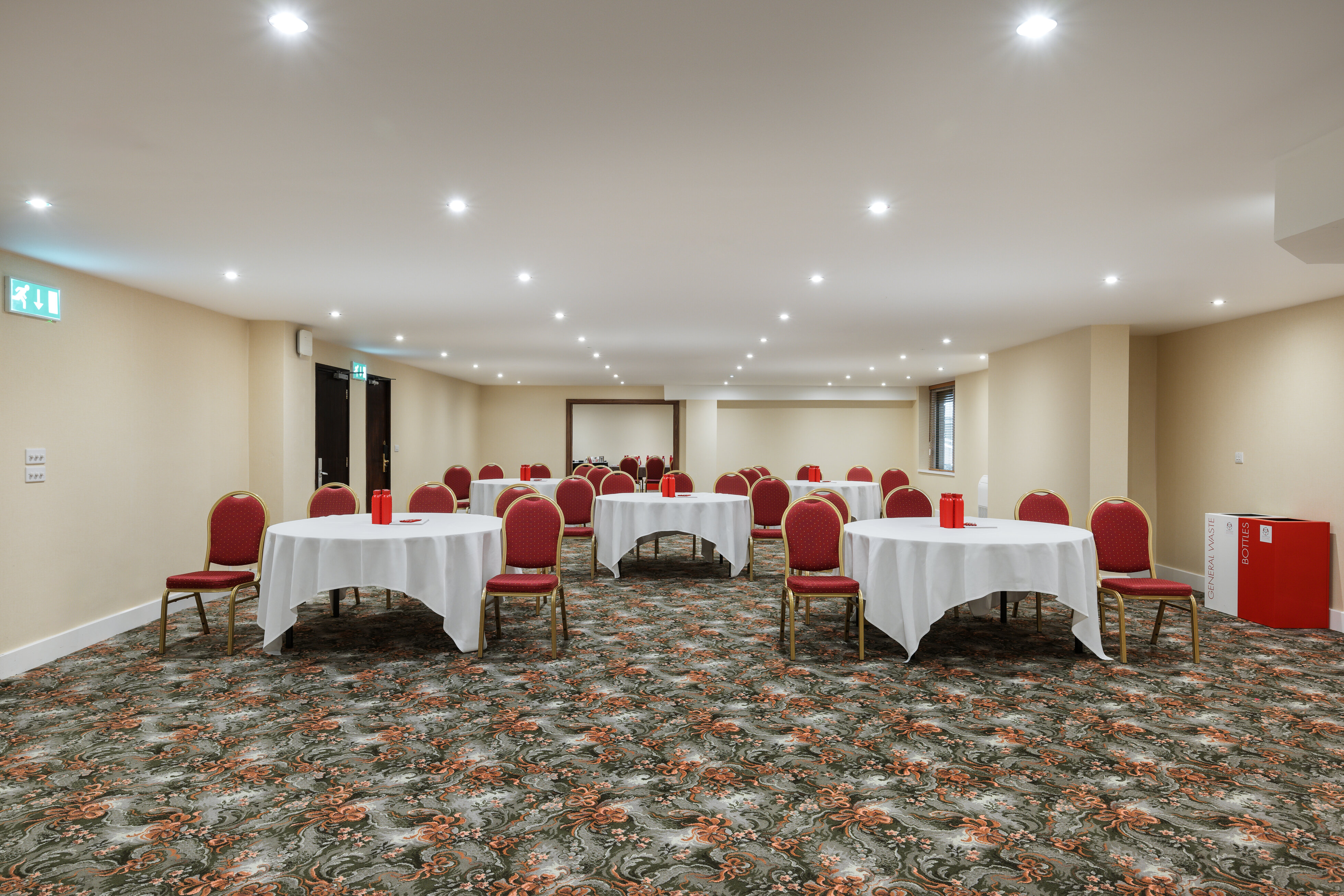 Cambridge Suite meeting space with round tables and red chairs in London Kensington.