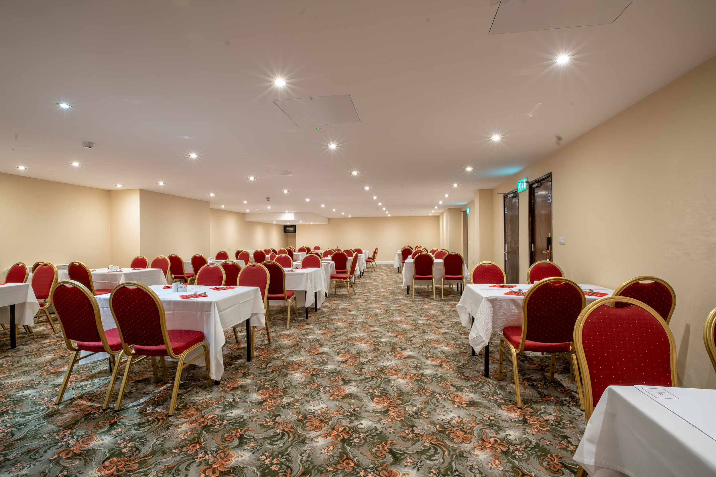Cambridge Suite at Millennium Gloucester: spacious meeting room with red chairs, ideal for events.
