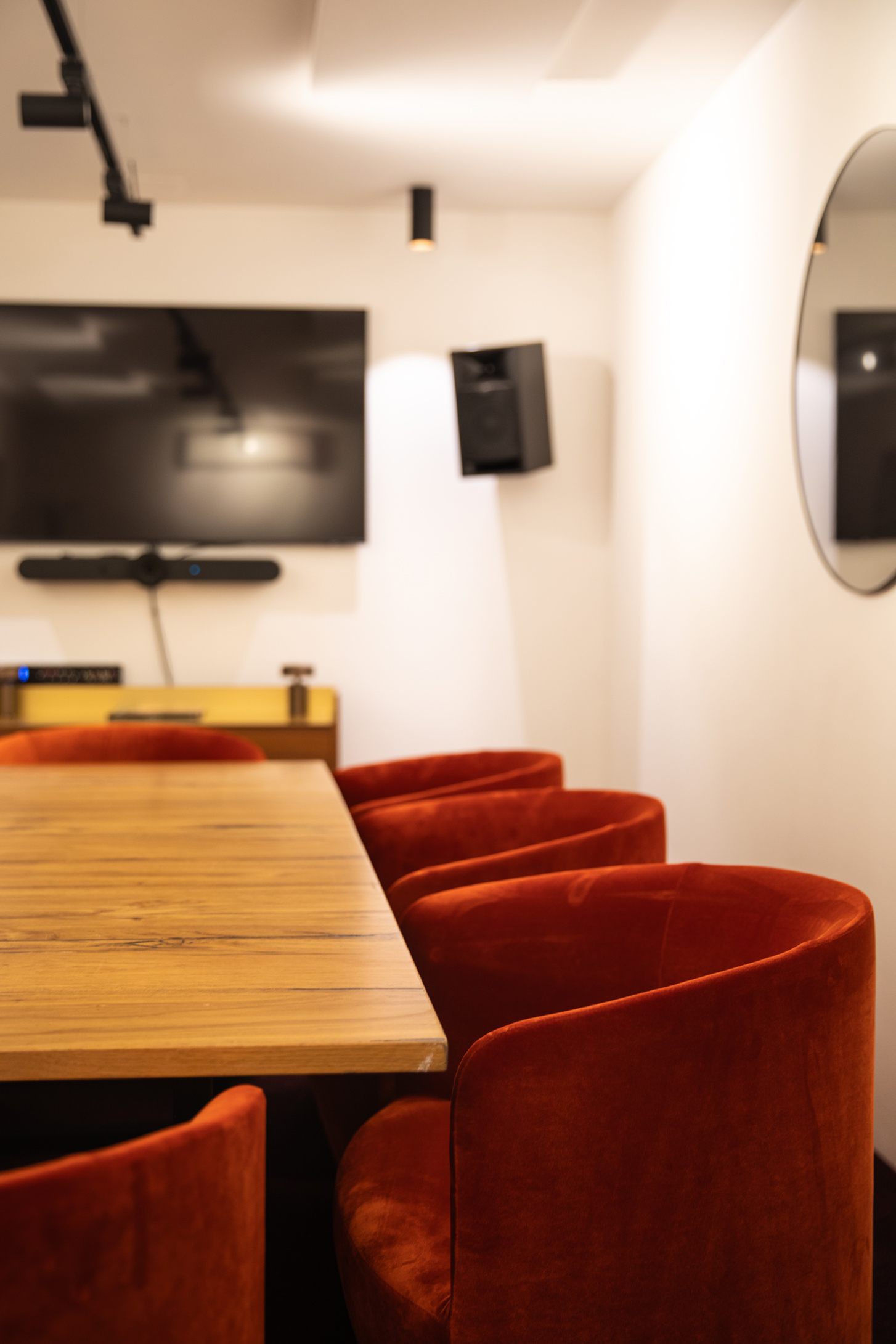 Modern meeting space with wooden table and orange chairs, ideal for presentations and brainstorming.