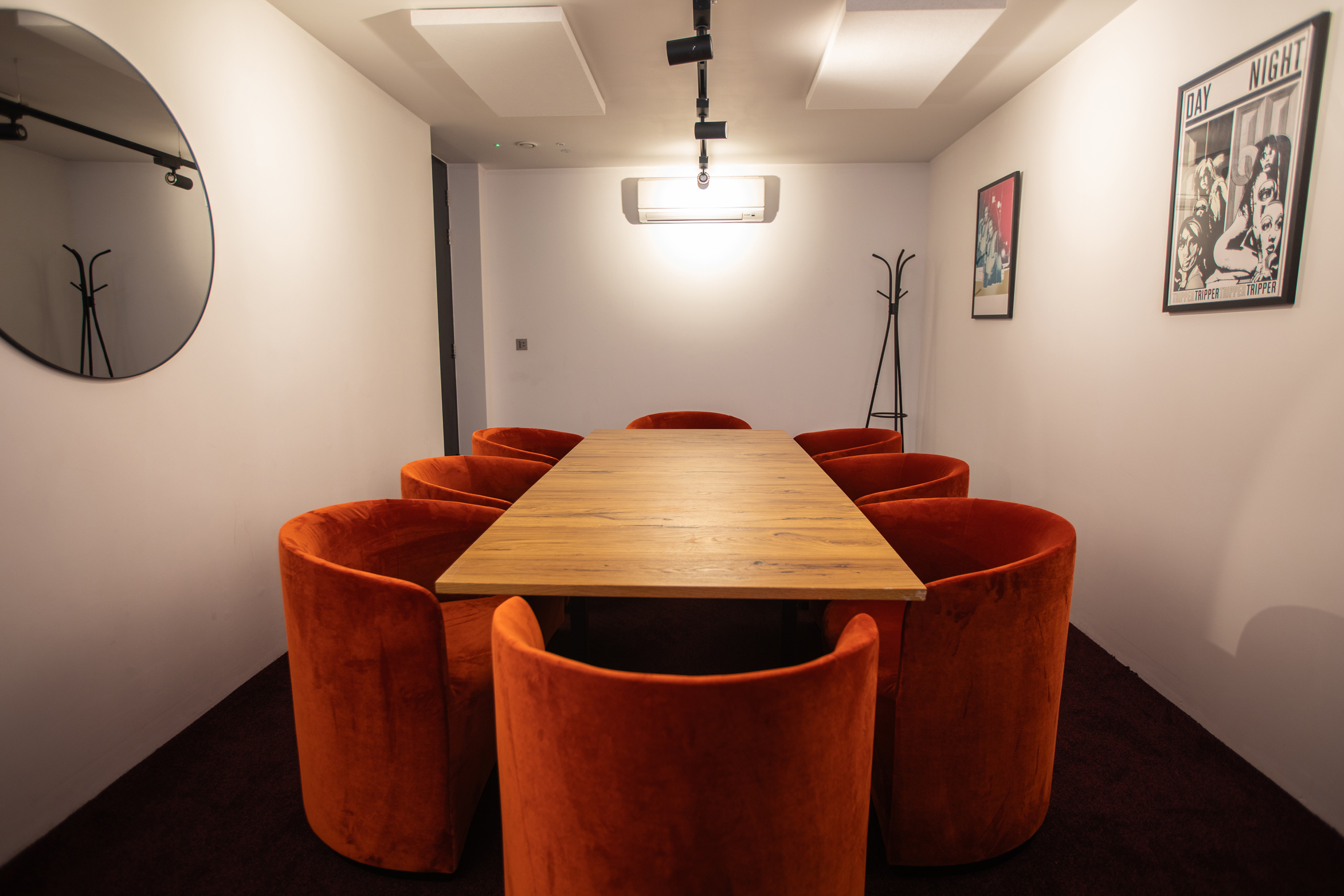 Modern meeting room with wooden table and orange chairs, perfect for collaboration events.