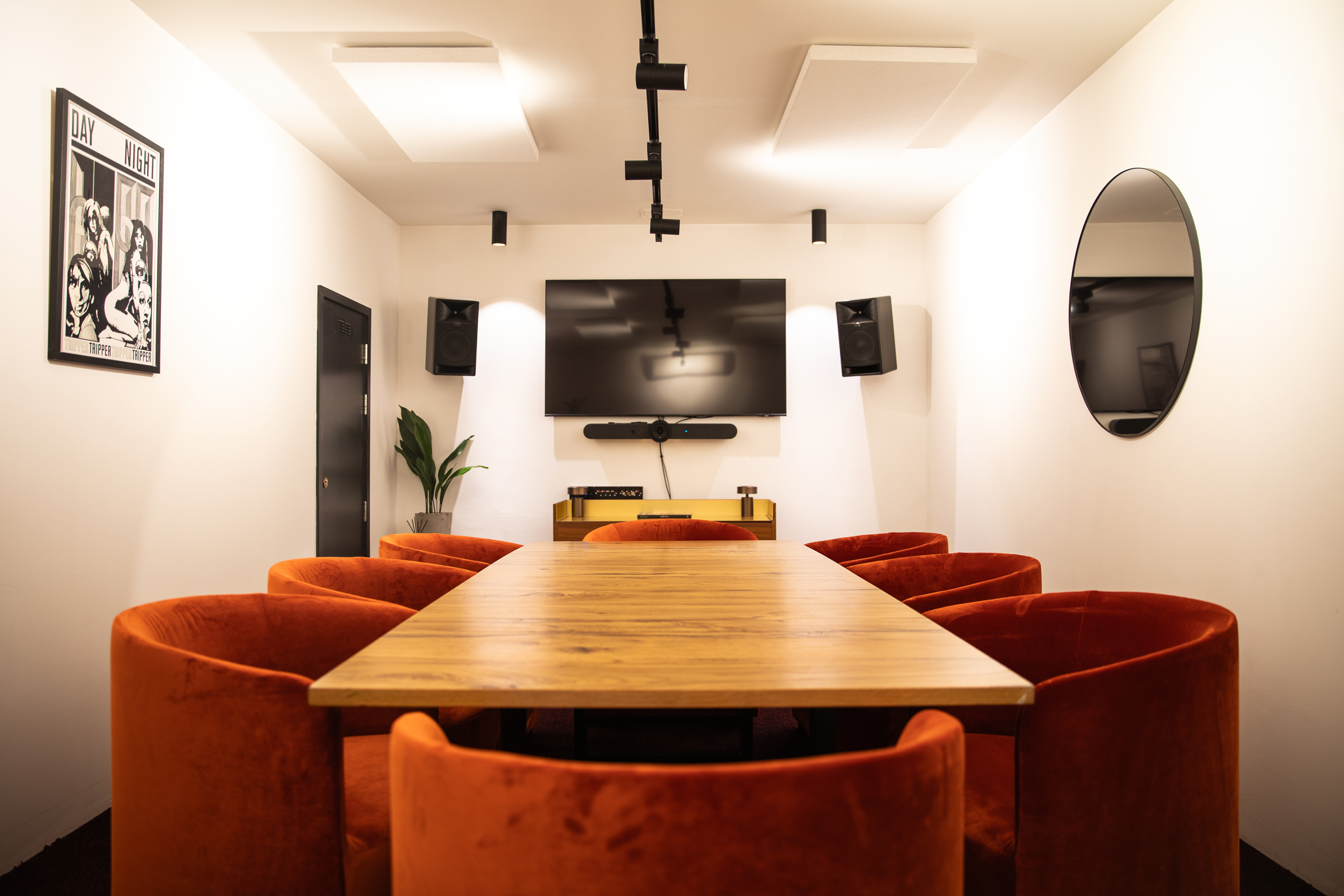 Modern meeting room with wooden table and orange chairs for collaborative events.