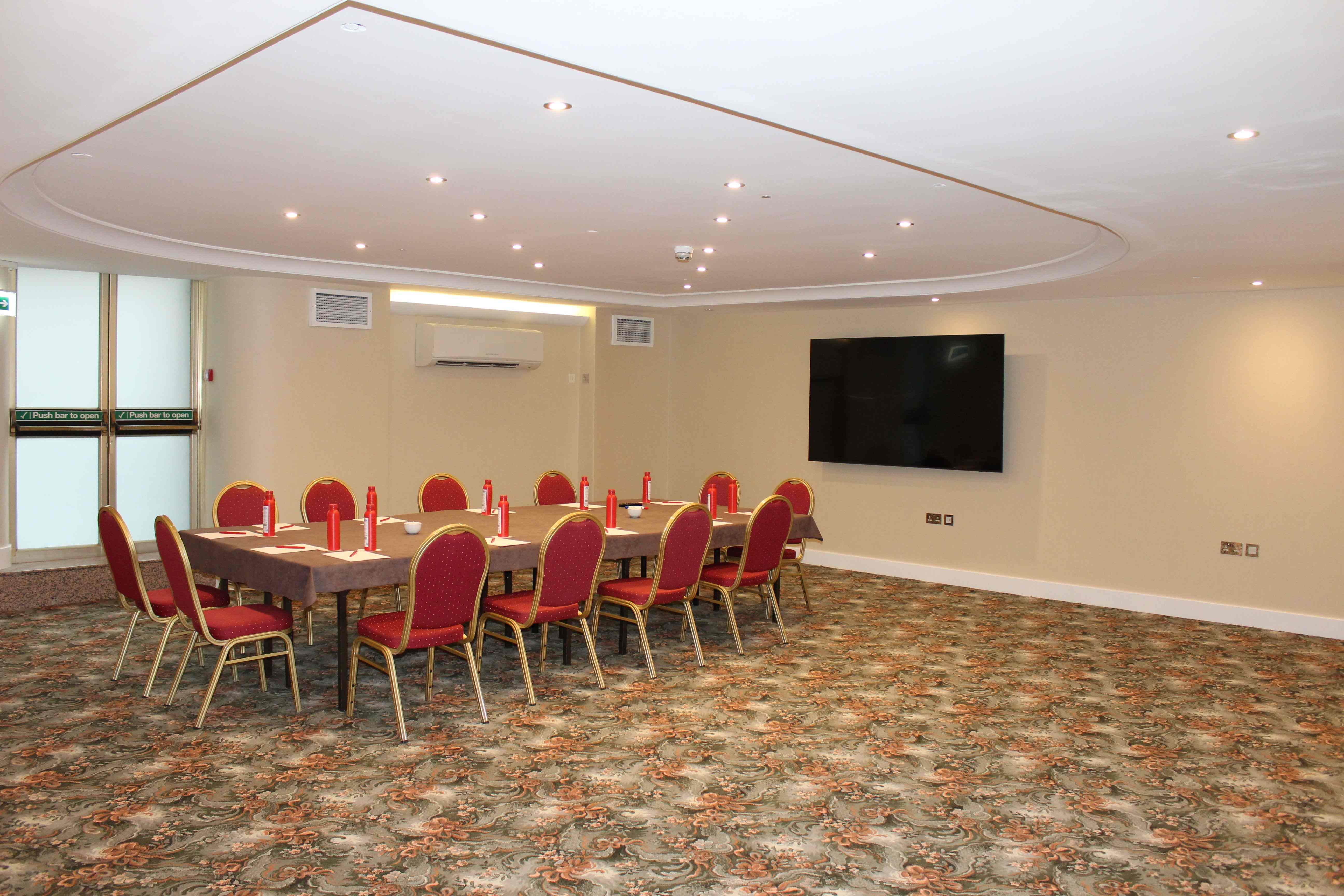 Oxford Suite meeting room with round table and red chairs, perfect for workshops and strategy sessions.