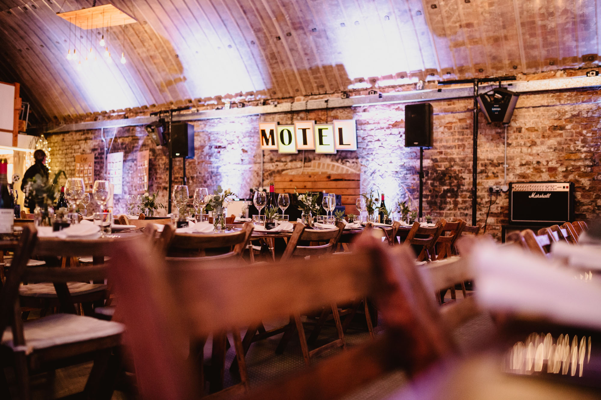 Rustic event space in Studio 3, MOTEL with wooden tables and floral centerpieces.
