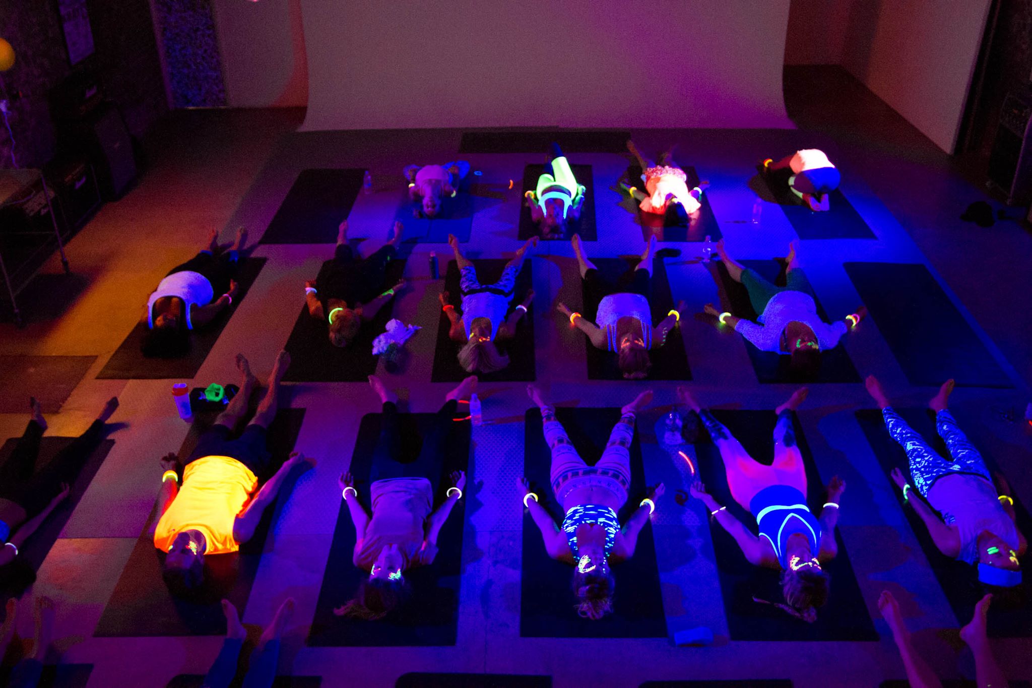 Vibrant group yoga session in neon lights at MOTEL Studio 3 for wellness events.