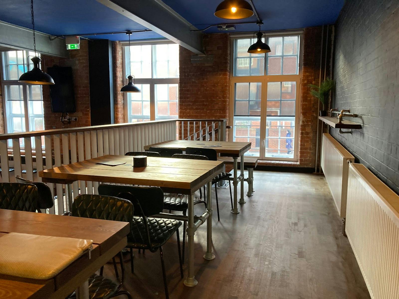 Versatile event space with wooden tables, ideal for meetings and networking events.
