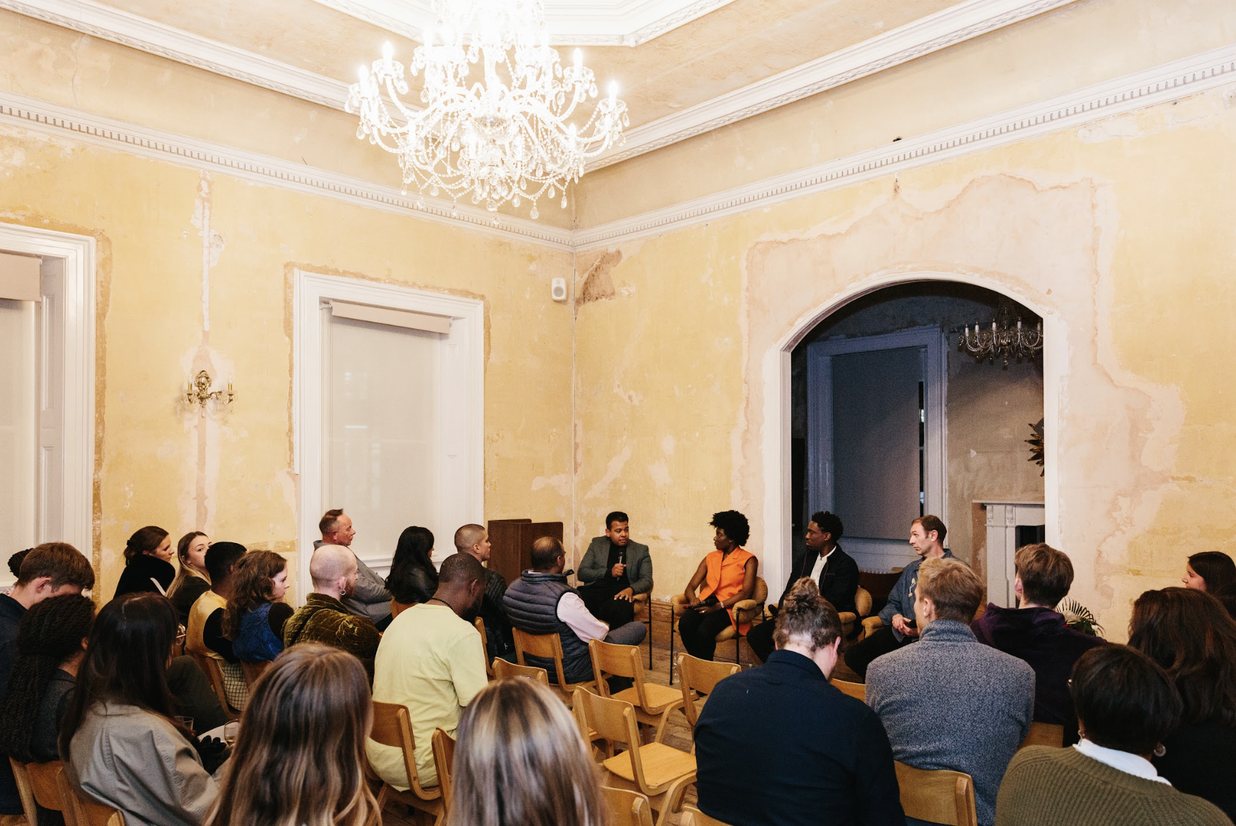 Panel discussion in Knotel Workclub with elegant chandelier, ideal for workshops.