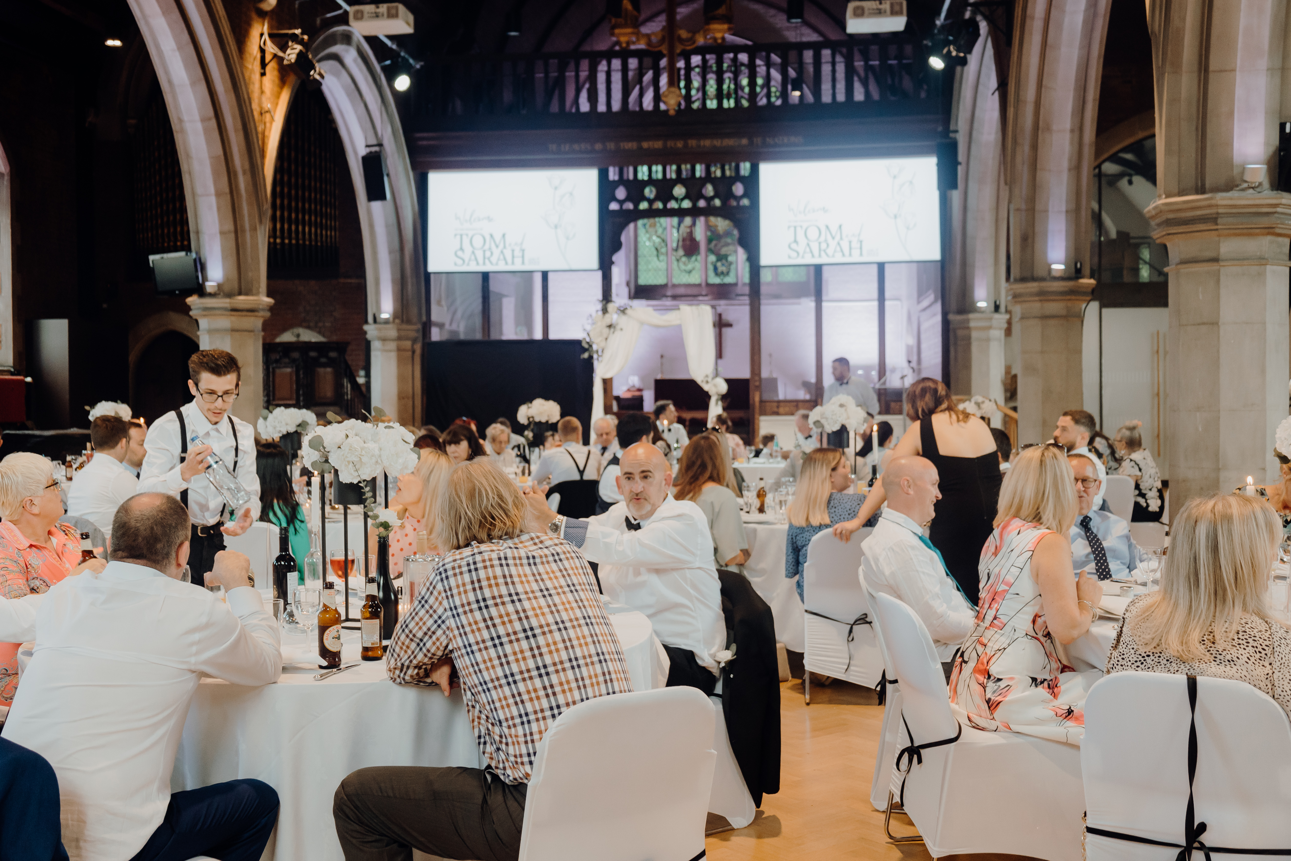 Elegant event in St Dionis Church with organized tables and multimedia presentations.
