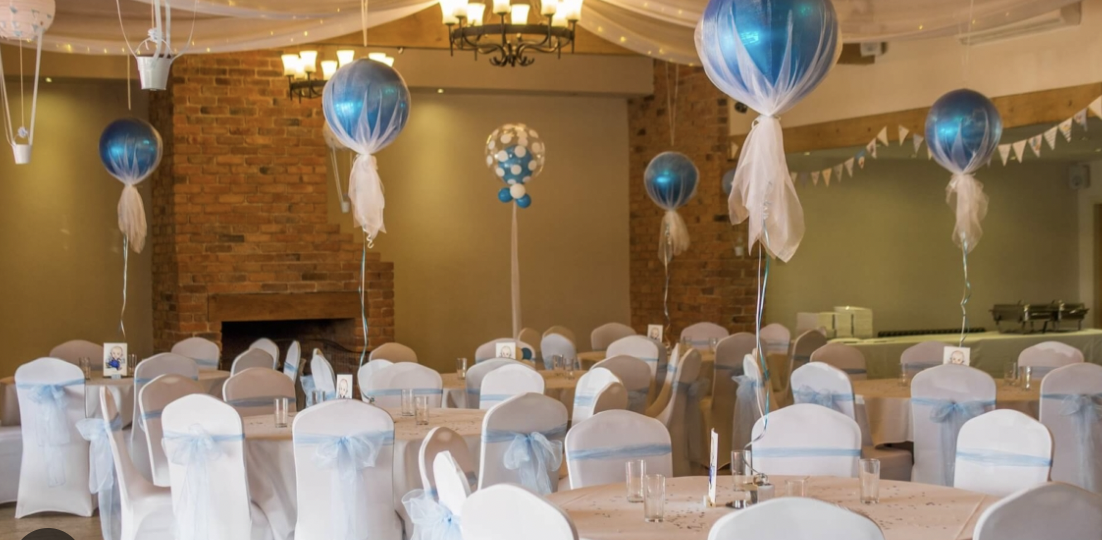 Baby shower event with blue balloons and elegant table settings in a festive space.