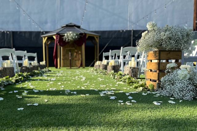 Outdoor wedding ceremony with floral gazebo and rustic decor at The Rustic & Chic Co.