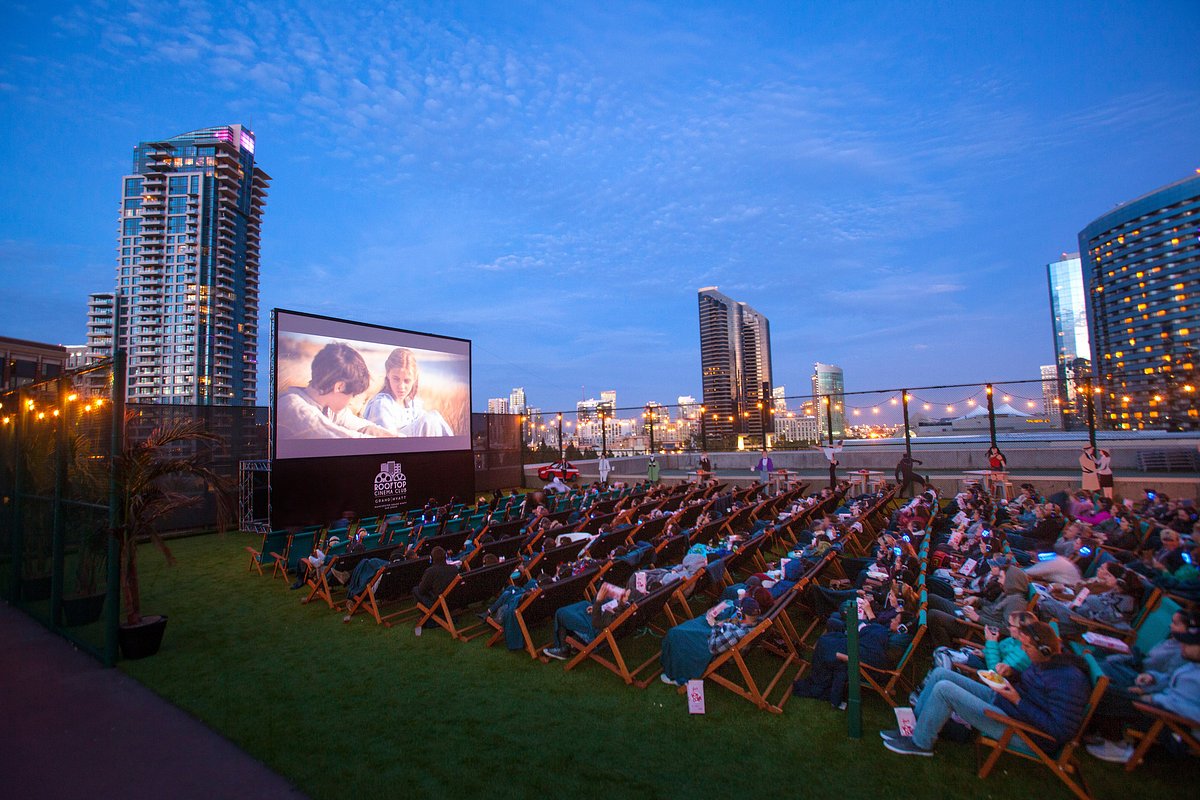Outdoor movie screening at Rooftop Cinema Club with urban skyline backdrop. Summer events.