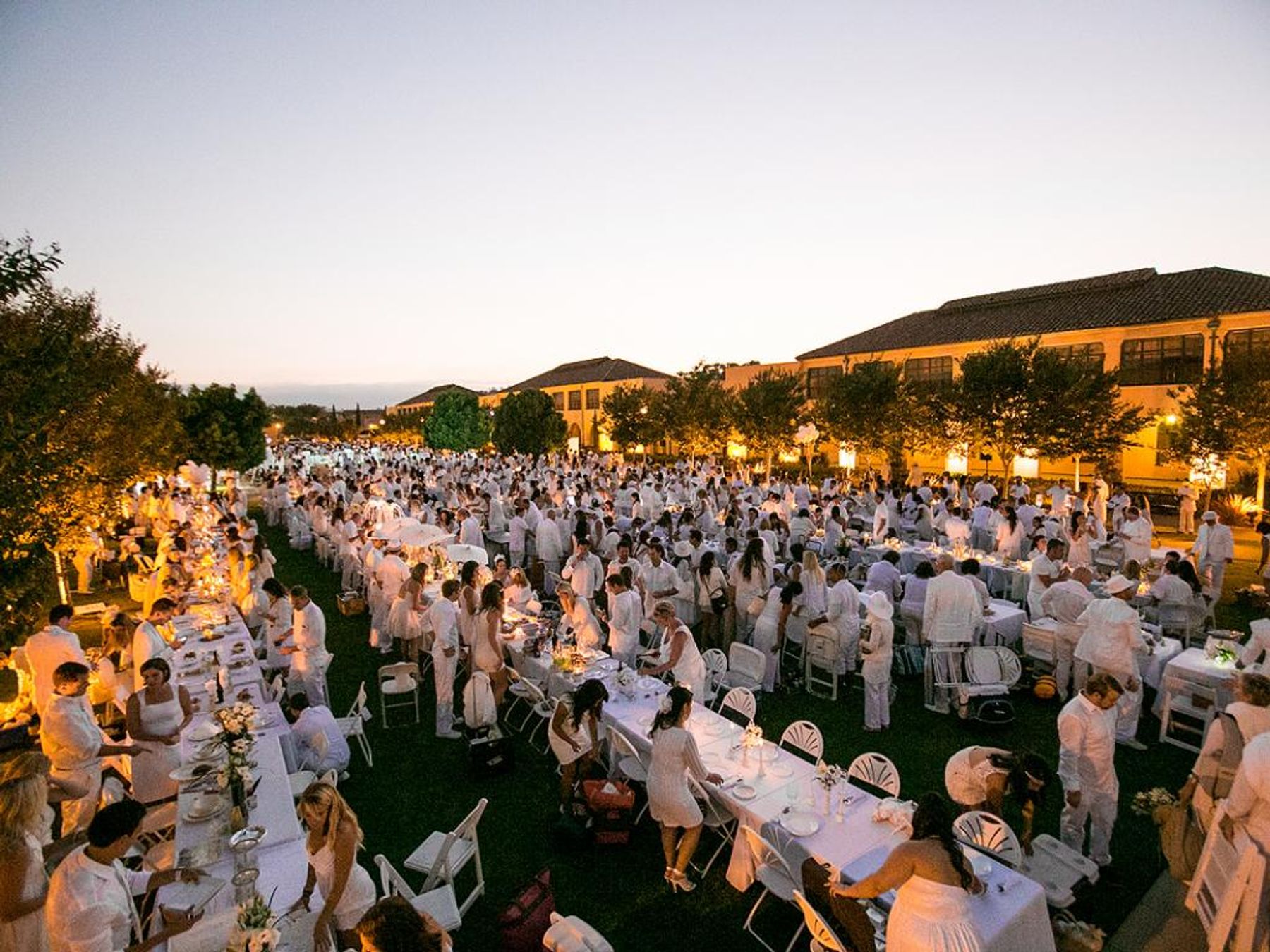 Elegant outdoor event at Liberty Station with white-dressed guests and twilight ambiance.