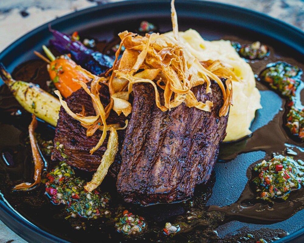 Gourmet meat dish with vibrant vegetables for upscale events at The Presley.