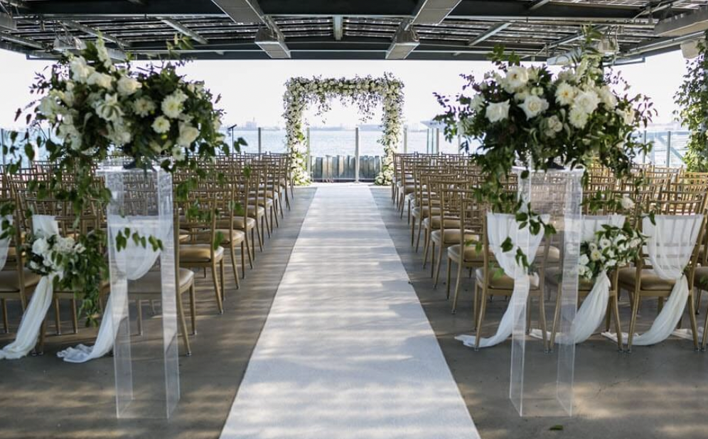Elegant wedding setup at Coasterra with floral aisle and greenery arch.