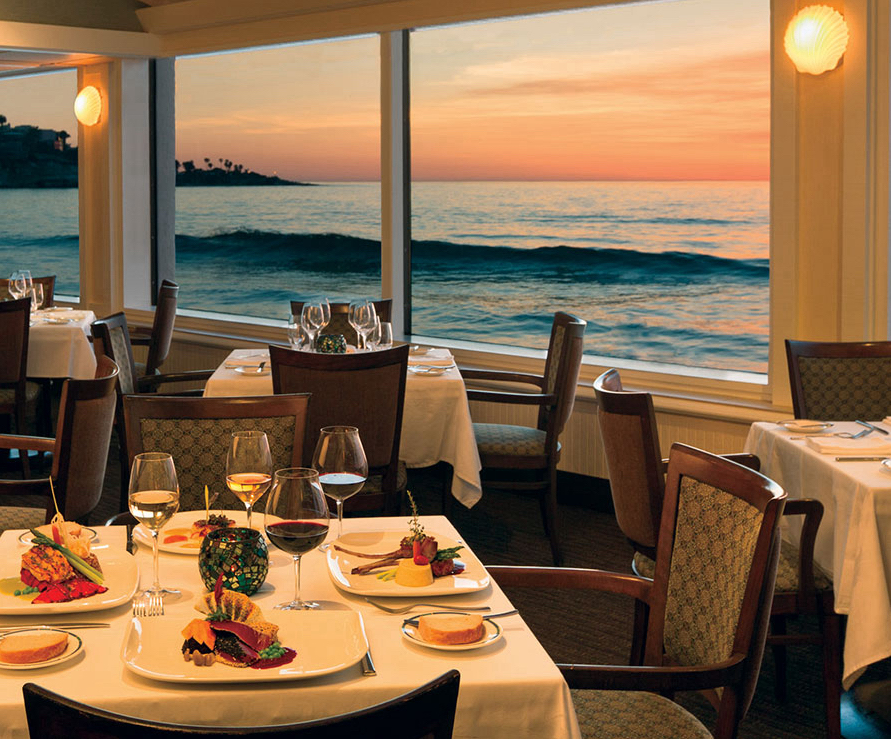 Elegant restaurant dining setup with ocean view at sunset, perfect for upscale events.