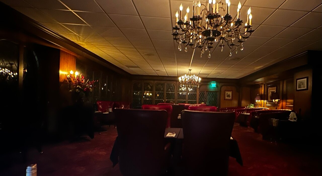 Elegant meeting space at Imperial Steakhouse with dark wood and plush red seating.