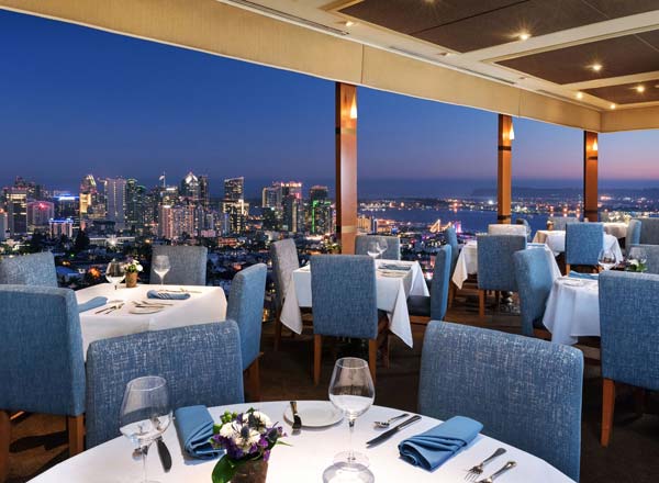Outdoor deck at Mister A's Restaurant with blue furnishings and city skyline views, perfect for upscale events.