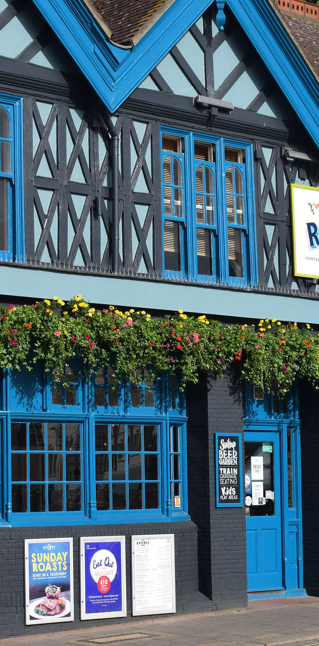Vibrant venue entrance with blue doors and flower boxes, ideal for outdoor events.